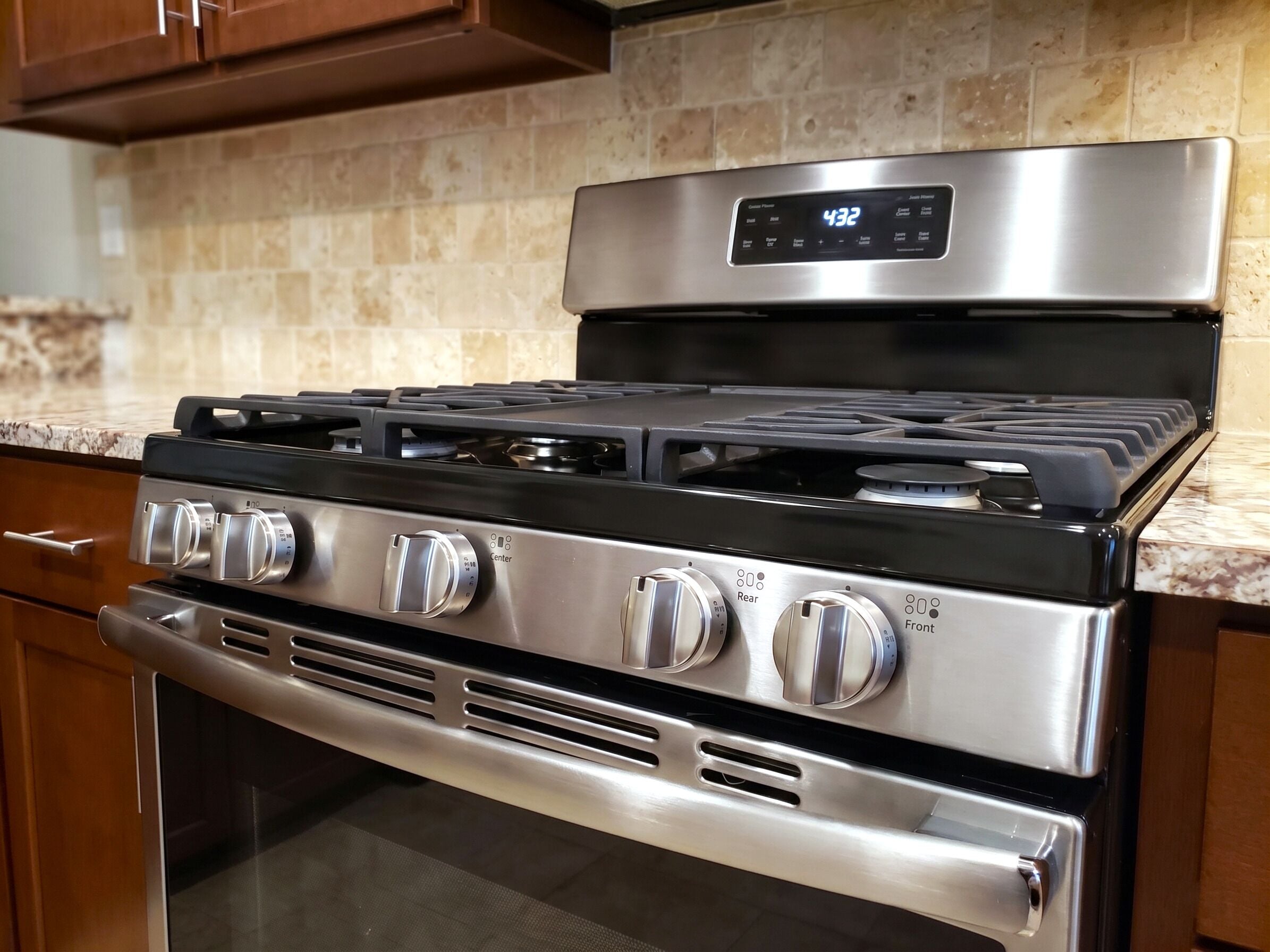 Une cuisinière en acier inoxydable dotée de quatre brûleurs, d’un écran numérique et d’un four intégré.