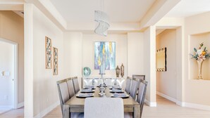 Un comedor con mesa de madera, sillas, una araña y obras de arte en las paredes.