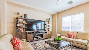 Una sala de estar con sofá, mesa de centro, televisor y estanterías decoradas.