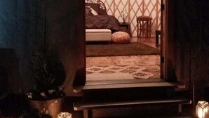 A yurt with a bed, pillows, and a small table. There are candles and plants outside. - Luxury Yurts on Lake Grapevine  (Southlake)
