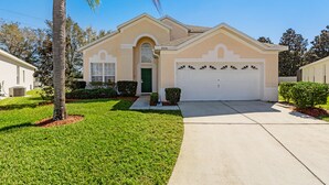 A single-story house with a beige facade, a green door, and a white garage.