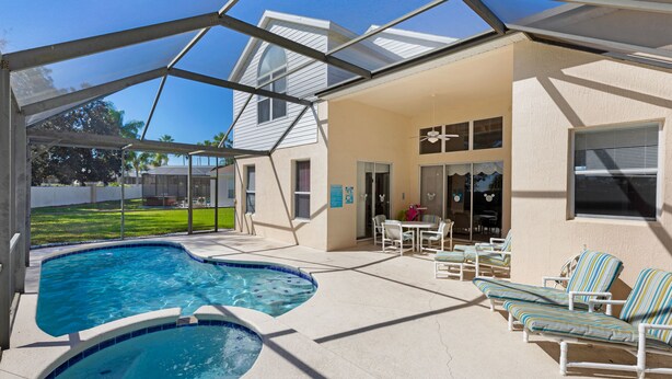 A covered outdoor swimming pool with lounge chairs and a patio area.