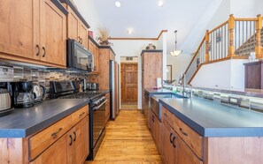 A modern kitchen with wooden cabinets, stainless steel appliances, and a wooden staircase. - Mountain View From Every Room (Breckenridge)