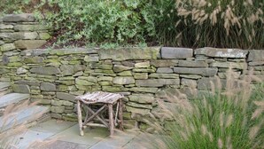 Un muro de piedra, un banco de madera rústico y un patio de piedra.
