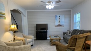 A living room with a sofa, two armchairs, a coffee table, a television, and a ceiling fan. - The Folly Jewel -  Sleeps 6 (Folly Beach)