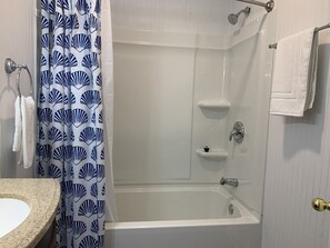 Baño con ducha, lavamanos y toallero.