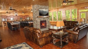 A spacious living area with a stone fireplace, leather sofas, and a television mounted on the wall. - Foxwood Mansion | Sleeps 44 | Amazing location (Gatlinburg)