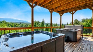 A wooden deck with hot tubs and a view of mountains. - Foxwood Mansion | Sleeps 44 | Amazing location (Gatlinburg)