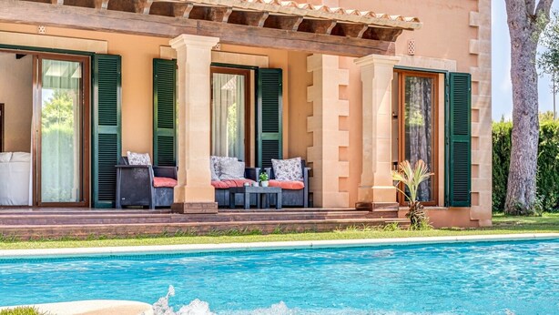 A poolside area with a built-in hot tub, outdoor seating, and a view of a pool.