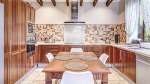 A modern kitchen with wooden cabinets, a central island, and a large window.