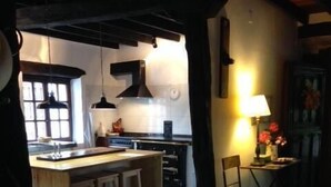 A kitchen with a central island, wooden stools, a dining table with chairs, and a tiled floor. - Llanos De Penagos: Mansion - THE BUMBARO'S HOUSE (Llanos de Penagos)