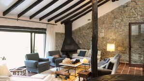A cozy living room with a stone wall, a fireplace, and modern furniture. - Llanos De Penagos: Mansion - THE BUMBARO'S HOUSE (Llanos de Penagos)