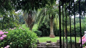 A garden pathway leading to a stone staircase surrounded by lush greenery and pink flowers. - Llanos De Penagos: Mansion - THE BUMBARO'S HOUSE (Llanos de Penagos)