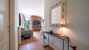 Una sala de estar moderna con un sofá, una mesa de centro y un televisor. Hay un comedor con una mesa y sillas.
