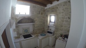 A compact kitchen with stone walls, a wooden ceiling, and a small window.