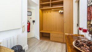 Habitación compacta con un armario de madera, una mesita con piñas y un extintor en la pared.