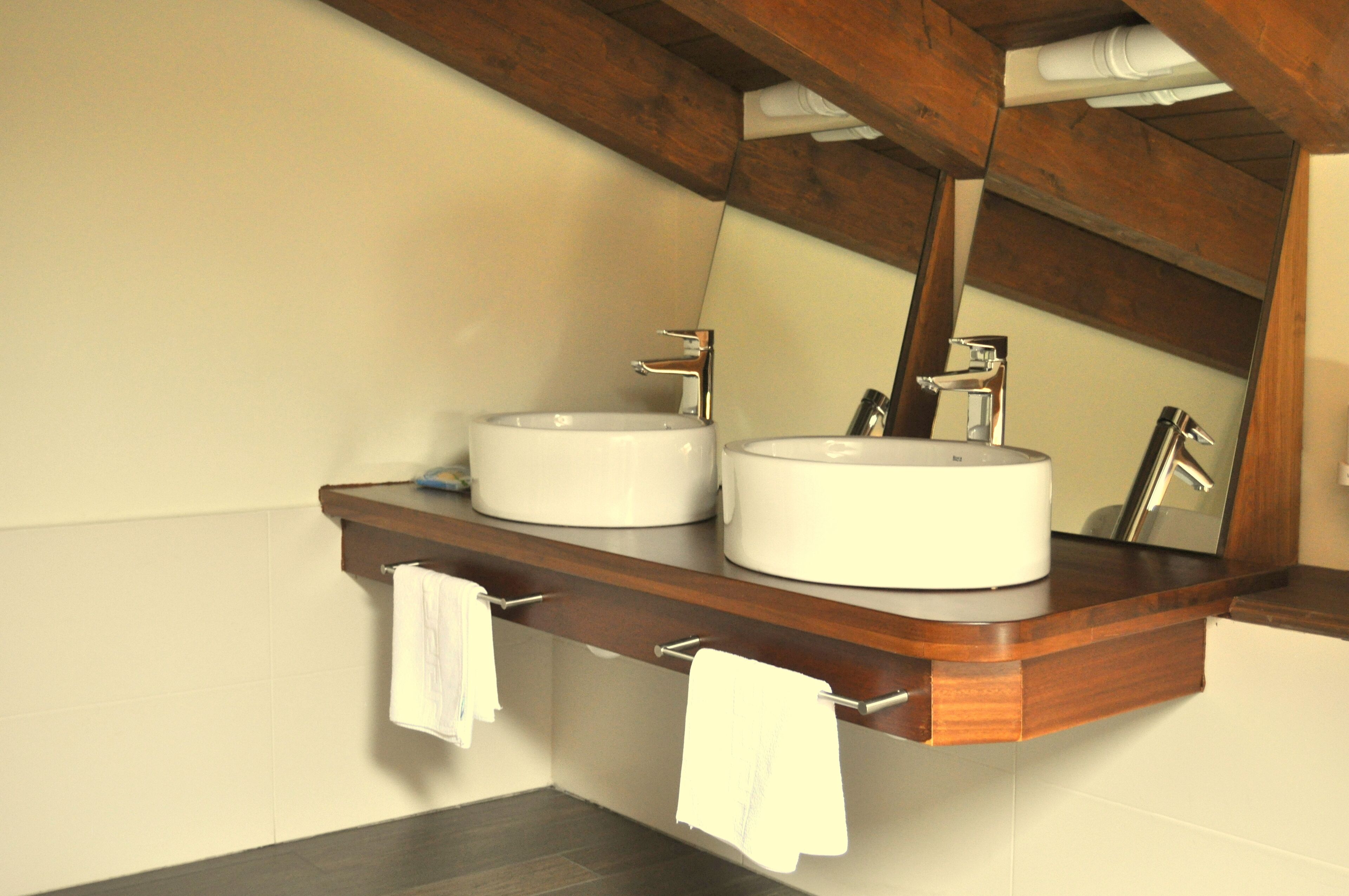 Ein Badezimmer mit zwei Waschbecken, einer Holztischplatte und einem Spiegel.