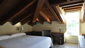 A bedroom with a large bed, a desk, and a chair. There is a window with a view of greenery outside. - Rural apartment Casona la Sierra for 5 people (Cudillero)