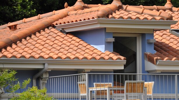 A building with a tiled roof, a balcony with a railing, and a table with chairs. - Rural apartment Casona la Sierra for 5 people (Cudillero)