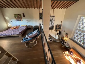 A spacious room with a large bed, a chair, and a small table. There is a window with a view of the outside. - The Casina Lorenzana (Lorenzana)