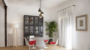 A dining area with a round table, white chairs with red cushions, a dark wooden cabinet, and a potted plant. - 3Dorm / 3bathroom Apt-Gran Via Madrid Center-Terrace (Madrid)