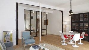A modern living room with a sofa, a blue armchair, a round dining table with white chairs, a bookshelf, and a glass partition. - 3Dorm / 3bathroom Apt-Gran Via Madrid Center-Terrace (Madrid)