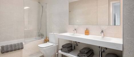 A modern bathroom with a glass-enclosed shower, a white sink, and a toilet.