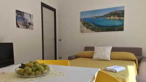 A room with a bed, a TV, and a table with fruit.