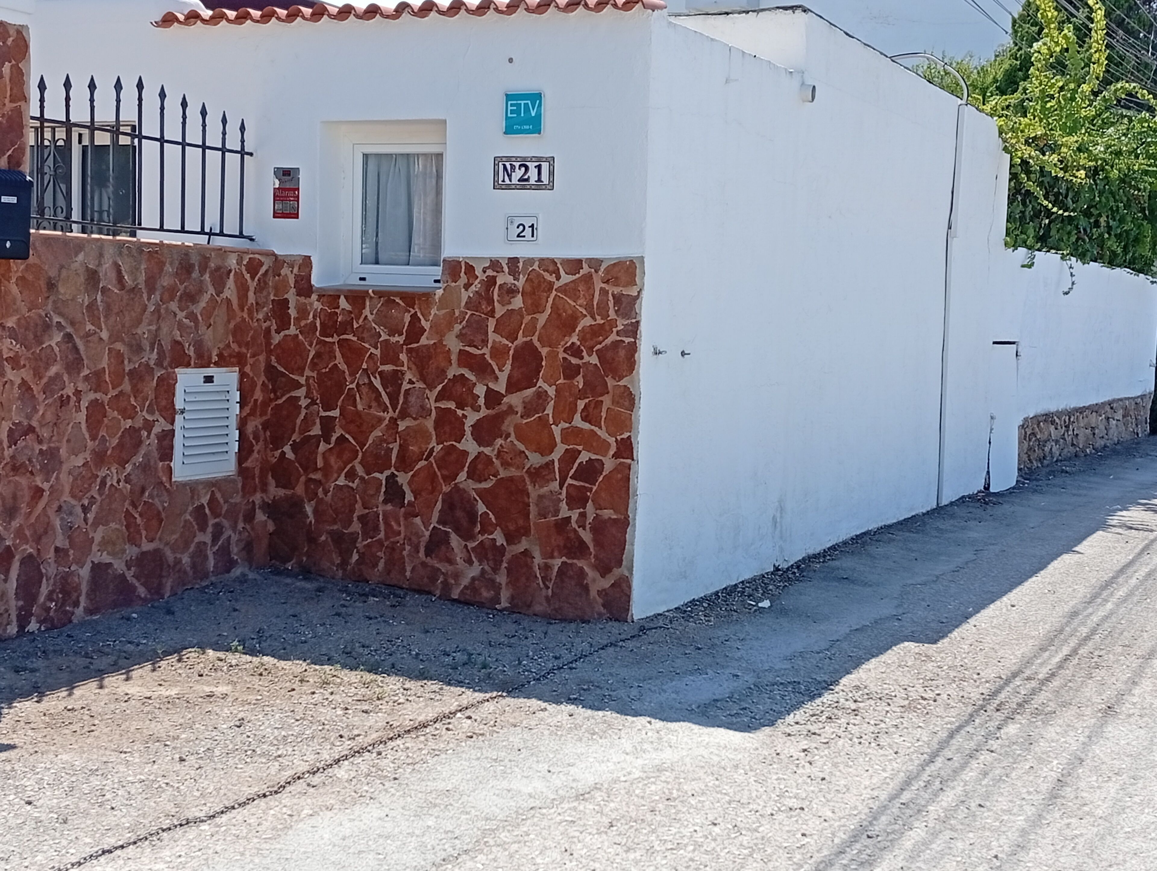 Un bâtiment à la façade en pierre, une fenêtre avec un rideau et une enseigne indiquant « N21 ».