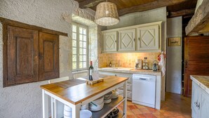 A rustic kitchen with wooden cabinets, a tiled backsplash, and a hanging light fixture. - Beautiful Old Bastide with private pool and heated Nordic bath, near Montcuq (Montcuq-En-Quercy-Blanc)