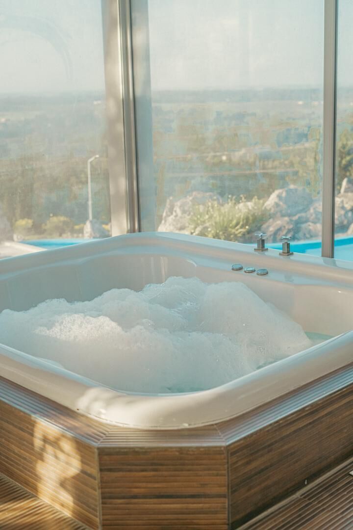 Un jacuzzi con vistas a un paisaje a través de amplias ventanas.