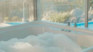 Un jacuzzi con vistas a un paisaje a través de amplias ventanas.