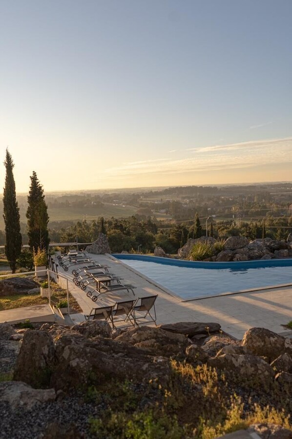 A poolside area with lounge chairs and a view of the landscape.