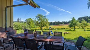 An outdoor patio with a wooden table and chairs, a bottle, and a glass. - Exclusive Country house Seewald - quiete area, Whirlpool, Sauna, large garten, bbq, wifi (Seewald)
