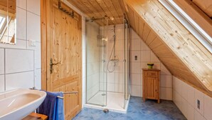 A bathroom with a wooden ceiling, a glass shower enclosure, a sink, and a small wooden cabinet. - Exclusive Country house Seewald - quiete area, Whirlpool, Sauna, large garten, bbq, wifi (Seewald)