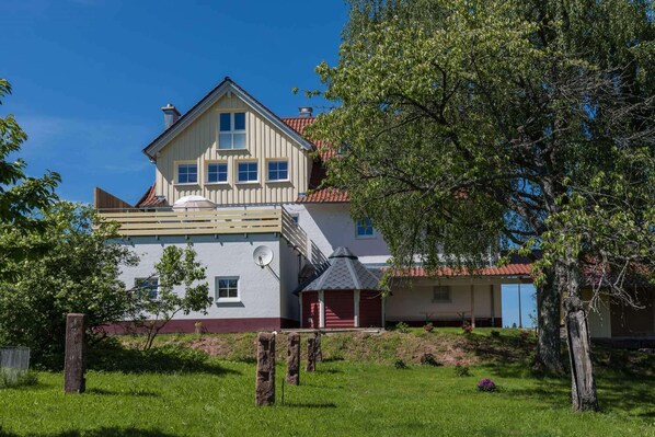 Een tweelaags huis met een rood dak, een balkon en een schotelantenne.