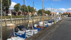 A marina with boats docked along a canal, surrounded by residential buildings. - Komf. Apartment, 5 pers., 3 bedrooms, 2 bathrooms, near Sankt Peter-O. , right on the dike (Tönning)