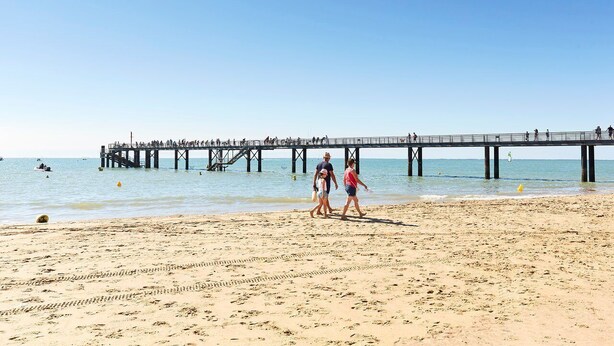 Una playa con un muelle que se adentra en el agua.
