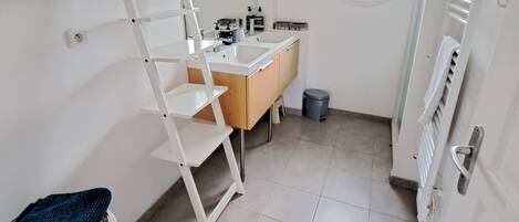 A small, bright bathroom with a white vanity, a mirror, and a window.