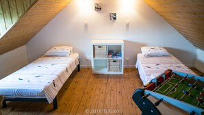 Quarto de sótão acolhedor com duas camas, um pequeno armário branco e uma mesa de futebol.