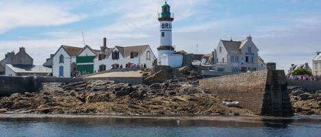 Eine Küstenstadt mit einem markanten Leuchtturm, Steinmauern und traditioneller Bebauung.