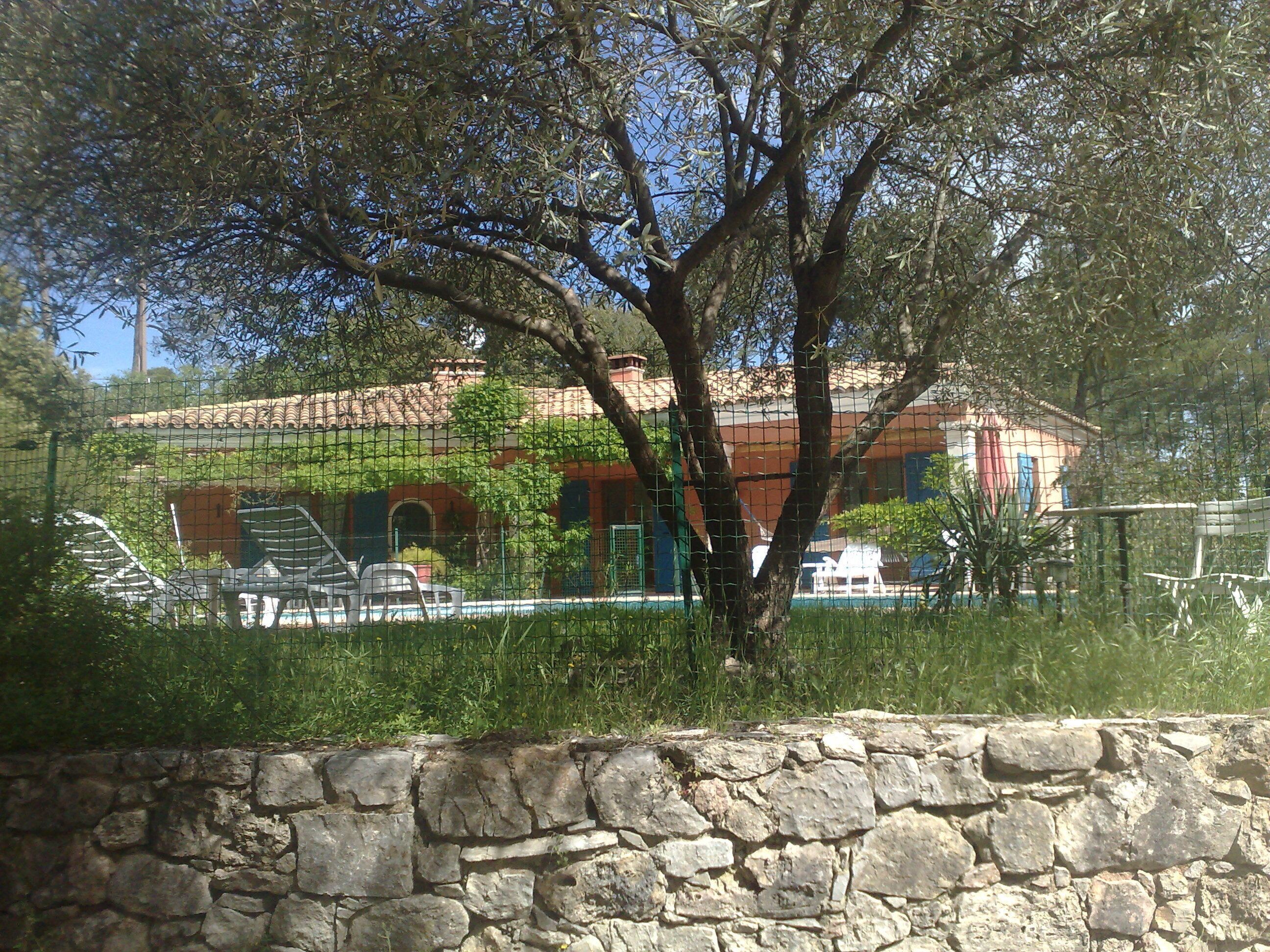 Un mur de pierre et une zone délimitée par une clôture, avec un bâtiment en arrière-plan.