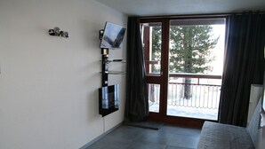A room with a sliding glass door leading to a balcony, a mounted TV, and a bed with a grey cover. - Apartment with balcony at the foot of the slopes - Arc 2000 (Bourg-Saint-Maurice)