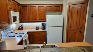 A kitchen with wooden cabinets, a white stove, a microwave, a toaster, and a refrigerator. - Quiet 
2 Bedroom/2 Bath Condo Sleeps 8 (Solitude)