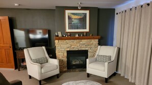 A living room with two armchairs, a fireplace, a TV, and a marble coffee table. - Quiet 
2 Bedroom/2 Bath Condo Sleeps 8 (Solitude)