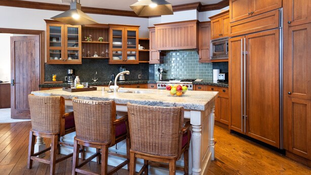 A kitchen with wooden cabinets, a granite countertop, a central island with chairs, and a hanging light fixture. - Vacation condo in Northstar village. Perfect location overlooking the mountain. (Truckee)