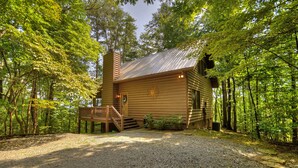 Une cabane en rondins dotée d’une terrasse en bois et d’un escalier menant à l’entrée.