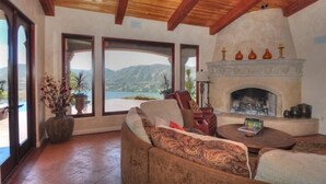 Un salon chaleureux avec une cheminée, de grandes fenêtres et une vue sur les montagnes.