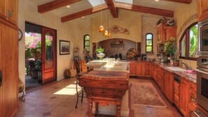 Une cuisine spacieuse avec des meubles en bois, un grand îlot central et un plafond voûté.