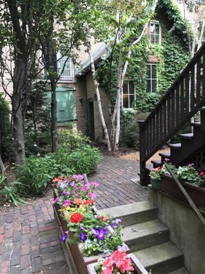 A brick pathway leading to a wooden staircase with flower boxes. - Peaceful Oasis in Top Chicago Neighborhood. Low Traffic, Pristine Cleanliness. (Chicago)